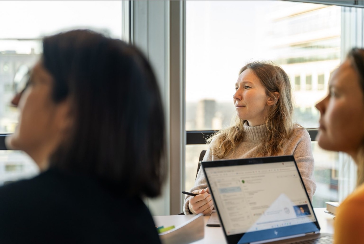 Three people in a meeting at the Portera office, one working on a laptop