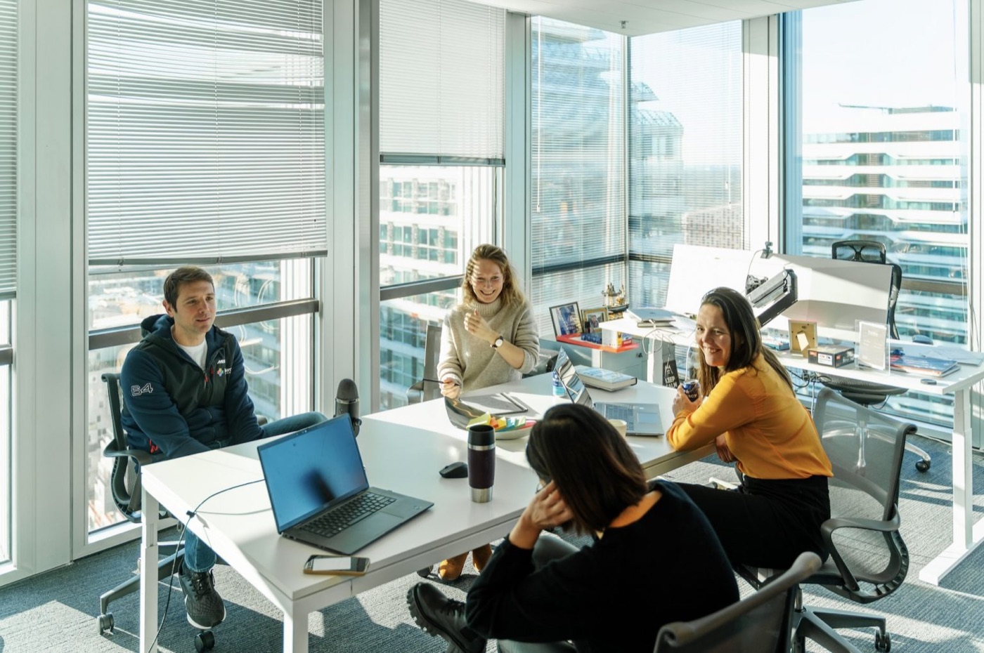Five people around a meeting table in a bright office, discussing the project